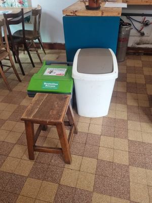 a small kitchen with a table and chairs and a trash can