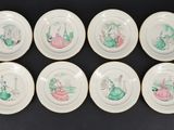 six white plates with green and pink designs on them on a black surface