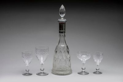 four wine glasses and a decanter on a table