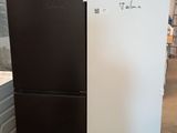 two black and white refrigerators sitting in a warehouse next to each other