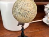 un petit globe posé sur une table à côté d'un vase