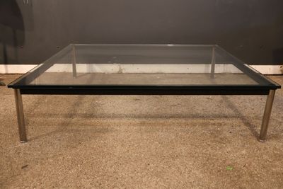 une photo d'une table basse en verre posée sur un sol recouvert de moquette