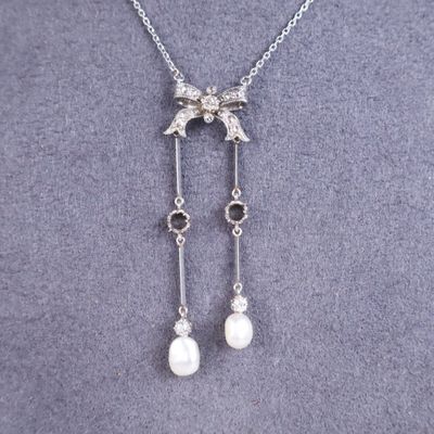 a close up of a necklace with pearls and a bird on it