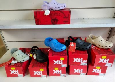 Plusieurs paires de Crocs sont alignées sur une étagère dans un magasin