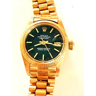 une photo d'une montre-bracelet en or avec un cadran vert