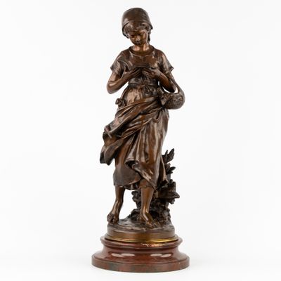une statue en bronze représentant une femme tenant un panier de fleurs