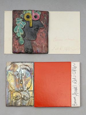 Plusieurs œuvres d'art sont exposées sur une table où se trouve un livre rouge