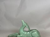 sculpture of a horse laying down on its back on a green base