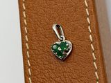 a close up of a leather case with a green heart charm on it