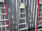 Plusieurs échelles sont alignées contre un mur devant un immeuble.