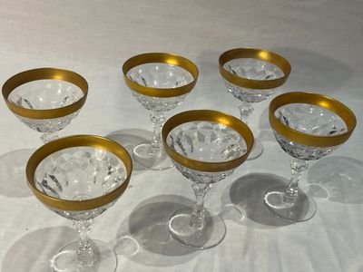 six verres à vin à bord doré posés sur une nappe blanche