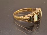 yellow gold ring with oplites and diamonds on a black surface