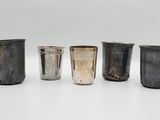 un ensemble composé de quatre coupes en argent et d'une coupe en argent posées sur une surface blanche