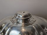 a silver plate with a silver lid on a table