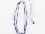un gros plan sur un collier de perles bleues orné d'un pompon