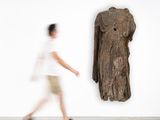 un homme passant devant une sculpture d'éléphant accrochée au mur