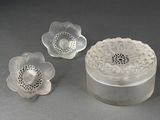 a glass container with a flower on it next to two smaller flowers