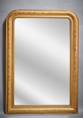 un miroir à cadre doré posé contre un mur gris