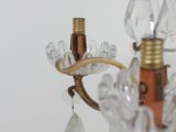 a glass chandelier with a gold base and a glass bead hanging from it