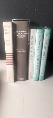 Plusieurs livres sont alignés sur une étagère devant un mur noir