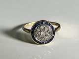 a close up of a diamond and sapphire ring on a white surface