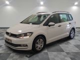 La Volkswagen Touran blanche est garée dans une pièce au sol carrelé en damier.