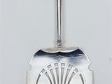 a silver spoon with a design on it on a white surface