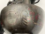 a black vase with a red design on it