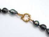 a close up of a black pearl necklace with a gold clasp