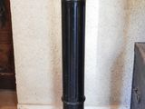 a black pedestal with a wooden base in the corner of a room