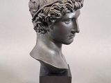 bronze bust of a young man with curly hair on a wooden base