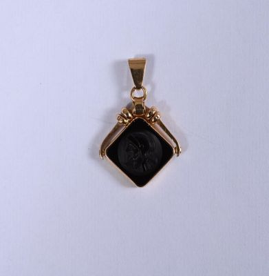 un gros plan d'un pendentif en or orné d'une pierre noire au centre