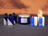 un bocal en verre bleu contenant une brosse à dents, du dentifrice et d'autres objets, posé sur une table
