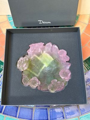 emballage d'une broche en forme de fleur rose, verte et jaune, dans une boîte noire posée sur une table en mosaïque