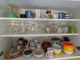 de nombreuses tasses et bols sur les étagères de la cuisine