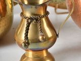 a gold pitcher and a copper bowl on a white table