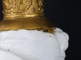 an antique white and gold vase with a gold hat on top of it