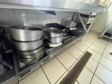 pots and pans sit on a shelf in a commercial kitchen