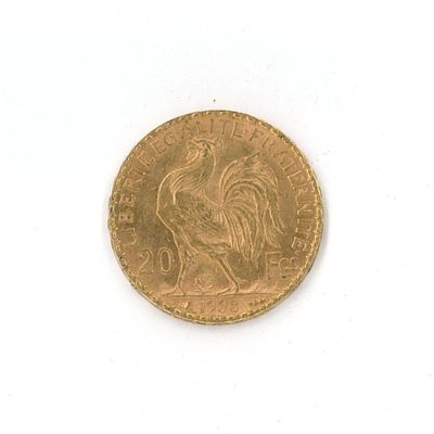 une pièce d'or ornée d'un coq sur une surface blanche