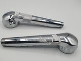 pair of chrome plated levers on a white surface