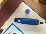 une tondeuse à cheveux bleue posée sur une table à côté d'un livre