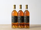 trois bouteilles de vin posées les unes à côté des autres sur une table en bois