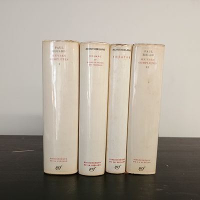 Trois livres sont alignés sur une table, avec un mur blanc en arrière-plan.