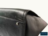 the back of a black leather purse with a metal clasp