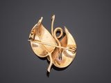 a close up of a gold brooch with a leaf on it