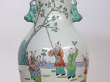 a white vase with a painting on it sitting on a table
