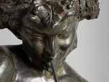 bronze statue of a boy with a pipe in his mouth