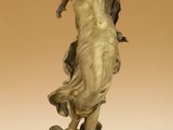 une statue antique en bronze représentant une femme tenant un oiseau dans la main
