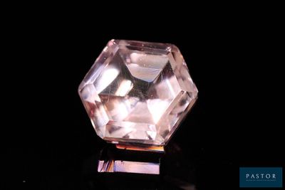 a close up of a pink diamond on a black surface