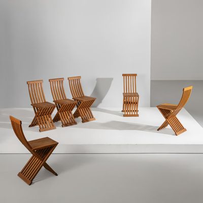 Plusieurs chaises en bois sont alignées sur une surface blanche